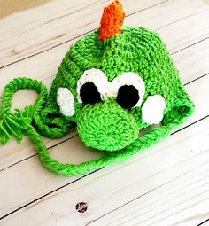 a green crocheted hat with an orange and white ear piece on top of it