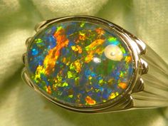 "As a rule the very best & highest quality stones are strictly reserved for our 14ct Gold range. Occasionally I set a few of the very best stones in the Sterling Silver range, this is one of those occasions. If you are prepared to pay a premium for the very best quality Opal , without the extra expense of a Solid Gold setting, this could suit. The ring is made from Sterling Silver & is Semi \"J\" backed with ornate workings. The Gem Plus grade Triplet Opal is 16x12mm Oval & of the highest qualit Classic Oval Opal Ring Collectible, Oval Multi-stone Gemstones For Collectors, Elegant Untreated Oval Gemstones, Untreated Oval Elegant Gemstones, Formal Multicolor Opal Ring, Multicolor Oval Opal Ring For Formal Occasions, High Luster Oval Gemstones For Gifts, Elegant Untreated Oval Opal Ring, Elegant Oval Untreated Opal Ring