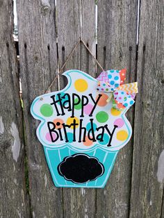 a happy birthday sign hanging on a wooden fence with polka dots and a cupcake