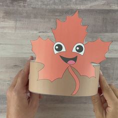 someone is holding up a paper cup with a leaf on it and the leaves have been cut out