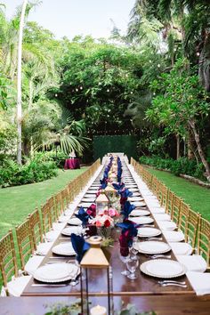 a long table is set with plates and place settings for an outdoor dinner in the garden