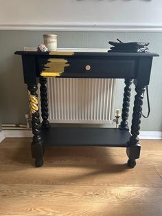 a black table with gold accents on the top and bottom, sitting in front of a wall