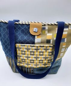 "This bright yellow/blue with a variety of geometric designs was made from upholstery samples. Each block is unique. The back of the purse has more green/blue combinations. The top is piped in bl/cream stripe with a navy blue 26\" set of straps. The purse is secured by vinyl tab and velcro. The tiny blue button gives is flair. The outside pocket also has velcro & 3 inside pockets give extra organization. The purse measures: h-15 1/2\"; w-11\"; bottom width'6 1/2\". Great as a purse or tote for o Retro Yellow Shoulder Bag For Daily Use, Yellow Everyday Bags With Pockets, Blue Reversible Rectangular Bag, Retro Yellow Tote Bag, Yellow Square Shoulder Bag For Daily Use, Everyday Yellow Bags With Pockets, Yellow Square Bag, Yellow Square Bags, Retro Yellow Shoulder Bag For Everyday