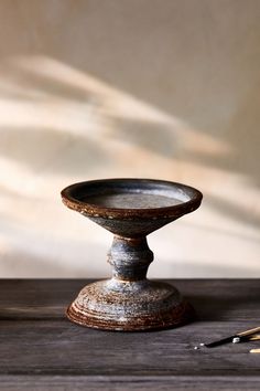 a wooden table with a metal bowl on top of it next to a pair of scissors