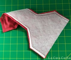 a piece of cloth is laying on a green cutting board with a red and white edge