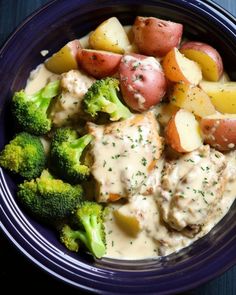 a blue bowl filled with potatoes, broccoli and meat covered in gravy