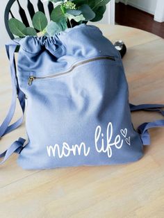 This mom life draw Sting Canvas Bag Is everything! It is Huge and perfect for fitting all your mama aka kids essentials Perfect for running out throwing snacks, wallet and diaper on the go instead of lugging that huge diaper bag around. 17 inches Long 14 1/4 inches wide 14.0 oz., 100% cotton Large main compartment Front zippered pocket with antique brass zipper Webbing straps Available in Black and Blue FOLLOW US ON SOCIAL MEDIA: Instagram: @righthereathome Facebook: @righthereathome Connect wit String Backpack, Mom Apparel, Mom Tote Bag, Bear Hoodie, New Mom Gift, Mama Sweatshirt, Backpack Purse, Gifts For New Moms, Black Tote Bag