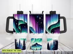 three travel mugs sitting on top of a wooden table with an image of mountains and trees in the background