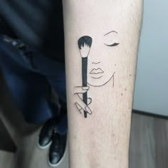 a woman's arm with a brush and eyeliner tattoo on her left forearm