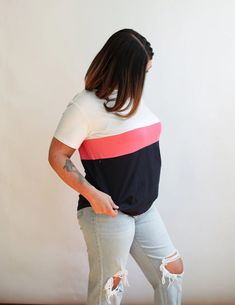 a woman standing in front of a white wall wearing ripped jeans and a t - shirt