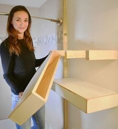 a woman standing in front of a shelf holding a cardboard box with the lid open