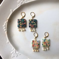 three pieces of jewelry sitting on top of a white plate next to a pair of earrings