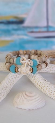 TitiTataStore.com Always FREE SHIPPING and a FREE GIFT! I Will Ship Within 24 Hours! Description: A set of 2 Coastal Style Beach Bracelets. The perfect accessory for that beach getaway vacation trip!  Materials:  8mm Natural Sandalwood Beads, 8mm Natural Wood Beads, Ocean Blue Cultured Sea Glass Nuggets Beads, 8mm Heishi Coconut Beads, and 8mm Lava Rock Heishi Beads.  A Sea Turtle and a Starfish charm adorned this Beachy set.  A high-quality elastic stretch cord is used to string the beads toget Cheap Round Stretch Bracelet For Beach, Sand-colored Adjustable Bracelet For Gift, Adjustable Sand-colored Bracelet Gift, Spiritual White Friendship Bracelets For Beach, White Coastal Style Bracelet For Gift, Bracelets Beachy, Coastal Bracelet, Ocean Theme Crafts, Girls Trip Gifts