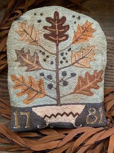 a stone with leaves and numbers on it sitting on top of some dry grass in front of a wooden surface