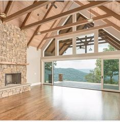 an empty living room with wood flooring and stone fireplace