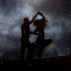 two people are dancing under the stars in the sky