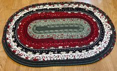 an oval rug on the floor with red and black colors, made to look like it is