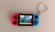 a keychain made out of legos on a white surface with a black, red, and blue object in the middle