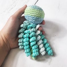 a hand holding a small crocheted object in it's palm