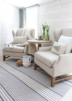 a living room with two chairs and a rug on the floor in front of a window