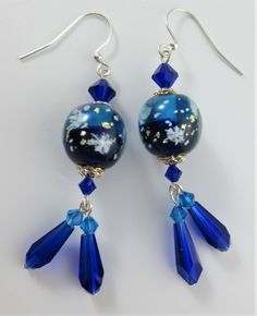 A lovely set of two tone blue winter holiday glass lampwork earrings.  These beautiful aqua and cobalt blue lampwork beads have little flecks of white as the snowflakes falling within.  They are a nice dangle pair with the rich blue teardrops hanging below with Preciosa bicones to set the colors off beautifully and dance together beneath the snowflake lampwork beads. The main lampwork beads have both silver and gold plated bead caps to give it that added sparkle.  The earwires are all silver pla Blue Jewelry For Christmas Party, Blue Christmas Party Jewelry, Blue Czech Glass Earrings For Party, Blue Christmas Jewelry For The Holidays, Blue Christmas Jewelry For The Holiday, Blue Beaded Earrings For Celebration, Blue Dangle Earrings For Celebration, Blue Earrings For Christmas Gift, Blue Dangle Jewelry For Celebration