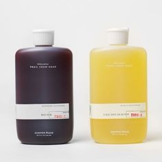 two bottles of liquid sitting next to each other on a white surface, one is yellow and the other is brown