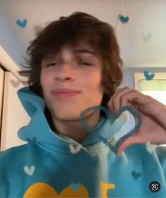 a young man in a blue hoodie is talking on the phone