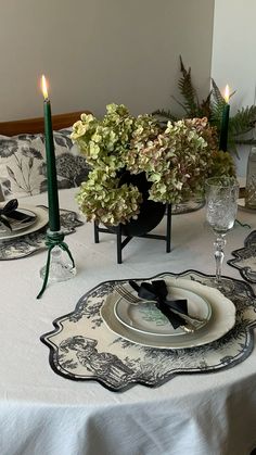 the table is set with black and white plates, silverware, candles and flowers