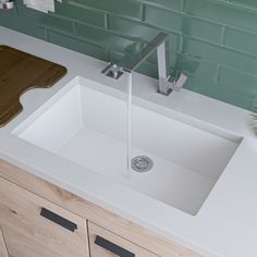 a white sink sitting under a faucet next to a wooden counter top in a bathroom