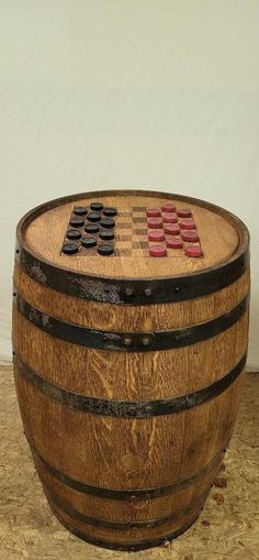 a wooden barrel sitting on top of a floor next to a white wall with a checkered flag painted on it