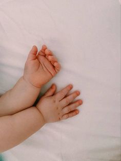 a baby laying on top of a white bed