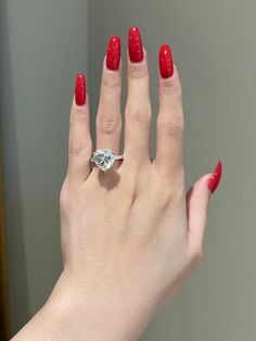 a woman's hand with red manicures and a diamond ring on it