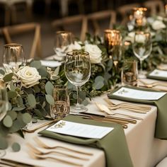 the table is set with green and white place settings, silverware, and greenery