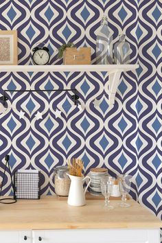 a kitchen with blue and white patterned wallpaper on the walls, shelves holding utensils