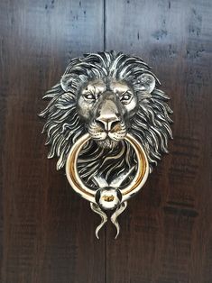 a metal lion head mounted to a wooden door with a ring on it's mouth