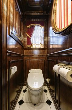 a toilet in the middle of a room with wood paneling on the walls and an american flag hanging from the ceiling