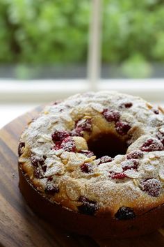 a bundt cake sitting on top of a wooden cutting board next to a window