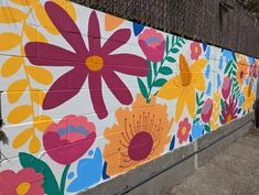 a painted flowered wall on the side of a building with a fence in the background