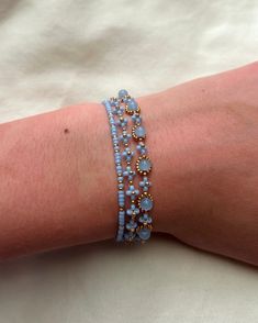 a woman's arm is covered in blue beaded bracelets with gold beads