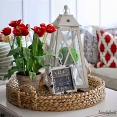 a basket with some flowers and a clock on the side table in front of a couch