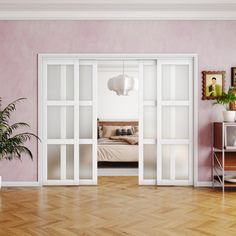 an empty room with pink walls and wooden floors, white doors open to reveal a bed