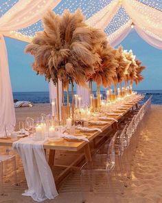 a long table set up on the beach with candles and pamolite centerpieces