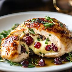 a white plate topped with meat covered in cranberry sauce and garnish