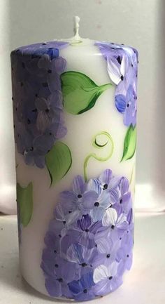 a white candle with purple flowers painted on it