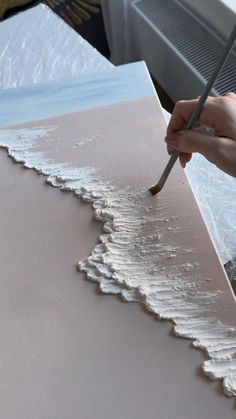 someone is painting waves on the surface of a large piece of paper with a paintbrush