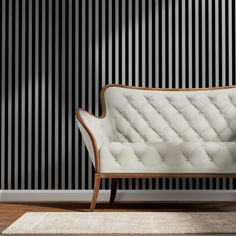 a white couch sitting on top of a wooden floor next to a black striped wall