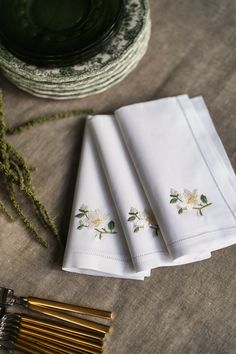 four white napkins with embroidered flowers on them