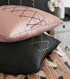 two pillows sitting on top of each other next to a nightstand with flowers in the background