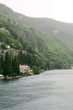 a large body of water surrounded by lush green hillside covered in lots of trees and houses