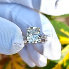 a close up of a person's hand holding an engagement ring